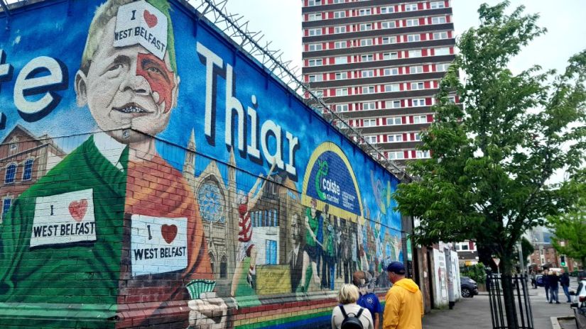 Tower block of flats behind high wall with murals.